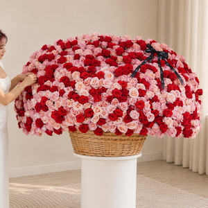 A large basket of 1000 red and pink roses in a wicker basket on a pedestal, held by a person.
