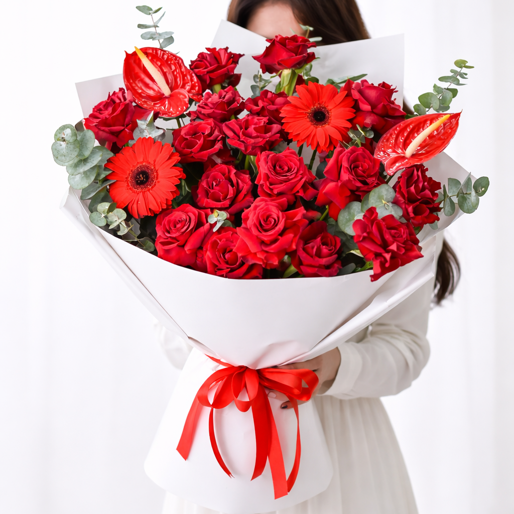 A lady holding a bouquet of red composi